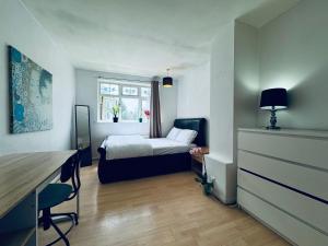 Renovu Exclusive Rooms London في لندن: غرفة نوم صغيرة مع سرير ومكتب