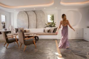 Eine Frau in einem Kleid geht in einem Wohnzimmer in der Unterkunft Aloni Hotel & Suites in Piso Livadi