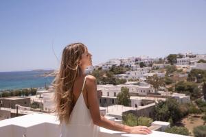 Una mujer con un vestido blanco mirando una ciudad en Aloni Hotel & Suites en Piso Livadi