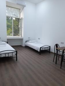 una habitación con dos camas y una mesa y sillas en White City Hostel, en Baku 36 fotos más