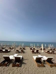 una playa con tumbonas y sombrillas y el océano en WaveBreeze Villas en Pafos