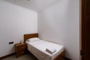 a small white bedroom with a bed and a nightstand at Araliya Beach Resort & Spa Unawatuna- Where you meet the sea all year in Unawatuna