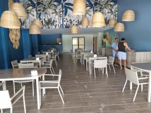two people standing in a restaurant with tables and chairs at Flat Eco Resort-Praia dos Carneiros in Tamandaré