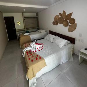 a hotel room with two beds and a table at Pousada Solar Dos Carneiros in Praia dos Carneiros