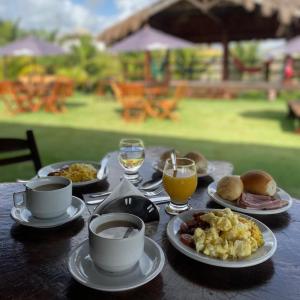 a table with plates of food and cups and drinks at Pousada Solar Dos Carneiros in Praia dos Carneiros