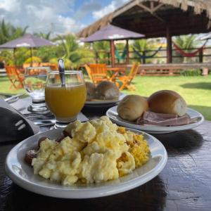 a table with plates of food and a glass of orange juice at Pousada Solar Dos Carneiros in Praia dos Carneiros