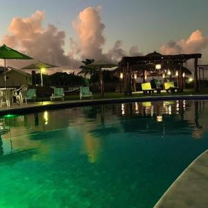 a swimming pool with chairs and a gazebo at night at Pousada Solar Dos Carneiros in Praia dos Carneiros