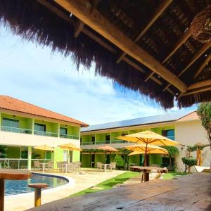 a resort with a pool and tables and umbrellas at Pousada Solar Dos Carneiros in Praia dos Carneiros
