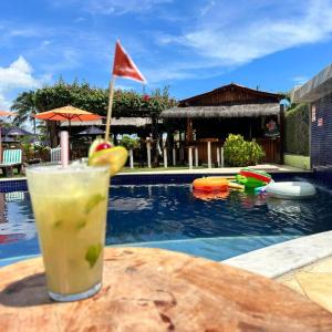 a drink sitting on a table next to a swimming pool at Pousada Solar Dos Carneiros in Praia dos Carneiros