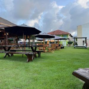 a group of picnic tables with umbrellas on the grass at Pousada Solar Dos Carneiros in Praia dos Carneiros