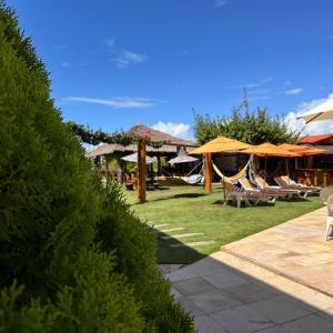 a yard with lawn chairs and umbrellas and tables at Pousada Solar Dos Carneiros in Praia dos Carneiros