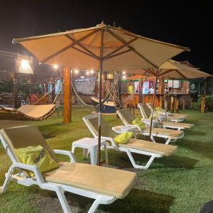 a row of lounge chairs with an umbrella and a playground at Pousada Solar Dos Carneiros in Praia dos Carneiros