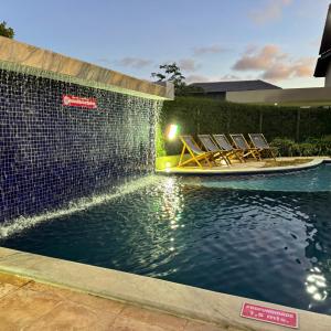 a pool with chairs and a boat in the water at Pousada Solar Dos Carneiros in Praia dos Carneiros