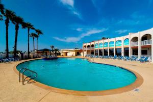 a large swimming pool with chairs and palm trees at Long Island Village Unit 111 in Port Isabel