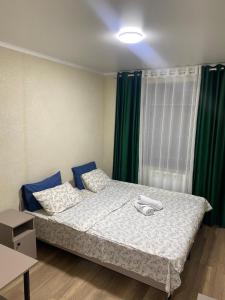 Cama en habitación con cortina verde en Нарэл en Bishkek