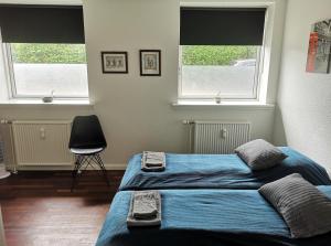 a bedroom with two beds and a chair and two windows at H&M Homes Apartments in Aarhus