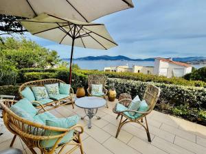 a patio with chairs and a table and an umbrella at Maison 4 pièces PIETROSELLA in Pietrosella