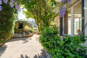a walkway next to a house with purple flowers at Hôtel La Garrigue & Bar Le Perchoir in Venasque