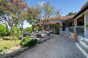 a house with a patio with tables and chairs at Hôtel La Garrigue & Bar Piscine in Venasque