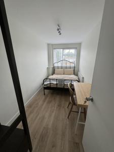 Habitación con cama, mesa y ventana en Brand new suit room 10 min to walk central line!, en Woodford