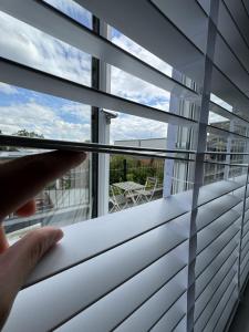 una persona mirando por una ventana con persianas en Brand new suit room 10 min to walk central line!, en Woodford