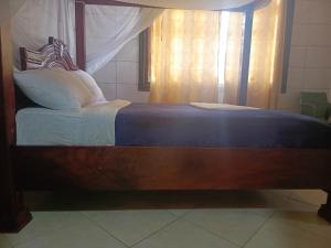 a large bed with a wooden frame in a room at Oasis Hotel and Guest House. Voi in Voi