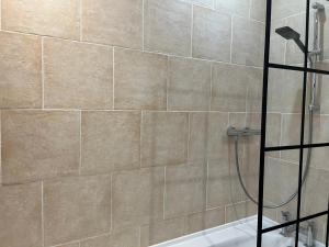 a bathroom with a shower with a tile wall at Cosy 3-Bedroom House 15mins to Olympic Village in Romford +20 photos