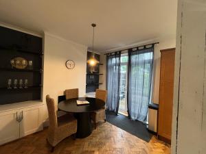 a dining room with a table and chairs and a window at Cosy 3-Bedroom House 15mins to Olympic Village in Romford