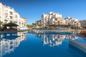 een zwembad met water in een resort met gebouwen bij Occidental Torremolinos Playa in Torremolinos