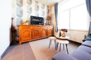 a living room with a tv on a wooden entertainment center at Lets Relax - Coté jardin in Mons