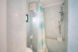 e bagno con doccia, servizi igienici e tenda per la doccia. di Casa La Stella - terrazza e vista sul mare a Ostuni