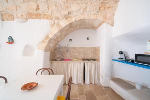 una cucina con un tavolo e un muro di pietra di Casa La Stella - terrazza e vista sul mare a Ostuni