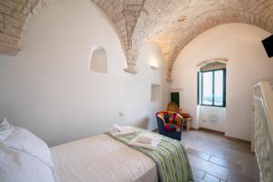 una camera da letto con un letto e una sedia in una stanza di Casa La Stella - terrazza e vista sul mare a Ostuni