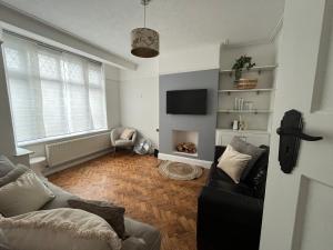 a living room with a couch and a tv at Cosy 3-Bedroom House 15mins to Olympic Village in Romford