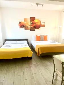 two beds in a hotel room with yellow sheets at 4-Tourist House Bologna-Studio - Self check-in in Bologna