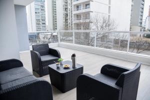 a balcony with two chairs and a couch and a table at Dpto Premium, 2 dorm, con balcón terraza y pileta in La Plata
