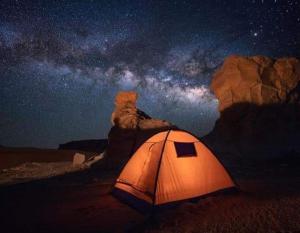 a tent in a field at night with the milky way at الصحراء البيضاء in Bawiti