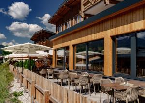 un restaurante al aire libre con mesas, sillas y sombrillas en Ferienalm Panorama Apartments en Schladming