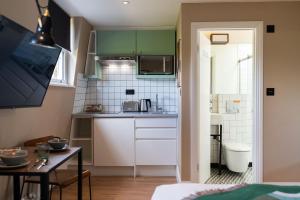 a small kitchen with green cabinets and a table at room2 Hammersmith Townhouse in London