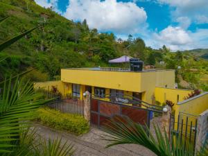 uma casa amarela no lado de uma colina em Hermosa casa de campo en GUATAPÉ em Guatapé