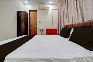 a bedroom with a large white bed in a room at Super OYO Hotel Orange in Surat