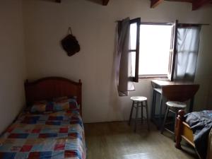 a bedroom with a bed and a desk and a window at Cometin in Malargüe