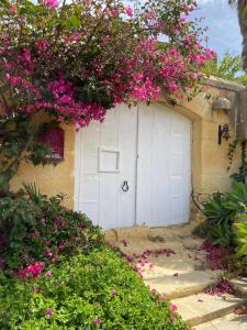 uma garagem branca com flores cor-de-rosa à frente em Farmhouse Dhyana em Għasri