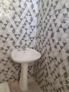 Baño con lavabo blanco y papel de pared geométrico en Belvedere Zakynthos Studios, en Vasilikos