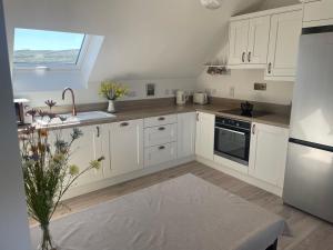 kuchnia z białymi szafkami i oknem w obiekcie Brand New Deluxe Sea View Apartment w mieście Inis Mor