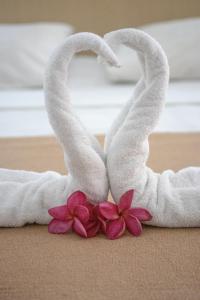 Dos cisnes de toalla con flores delante de una cama en Flat Pipa Oceano, en Pipa
