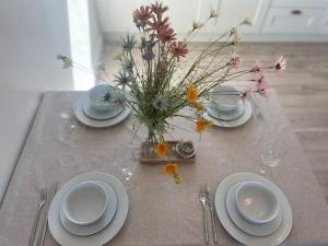 uma mesa com pratos e um vaso de flores em Brand New Deluxe Sea View Apartment em Inis Mór