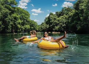 two girls are sitting on rafts in the water at A Rustic Romantic Getaway in Texas Hill Country in San Marcos