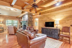 a living room with a leather couch and a television at Rogers Cabin on 17 Acres with Wraparound Deck! in Rambo Riviera