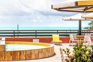 un patio con piscina, sillas y sombrilla en Flat Pipa Oceano, en Pipa